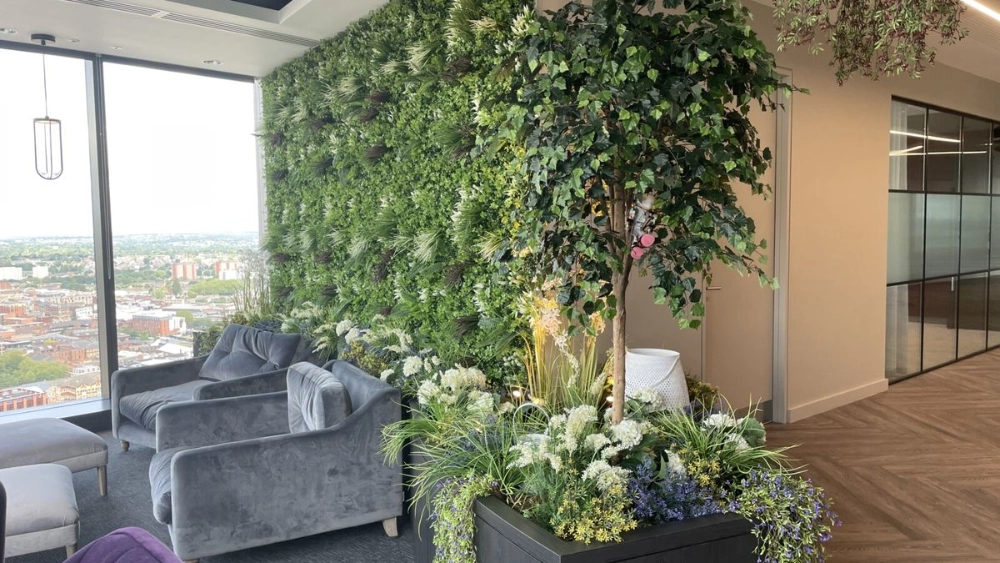 Green wall in an office with a pot plant next to it