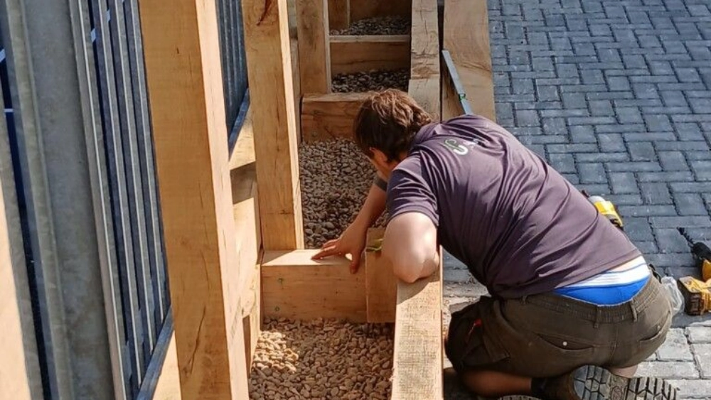 Man looking at the bottom of a wooden box where plants will be planted in