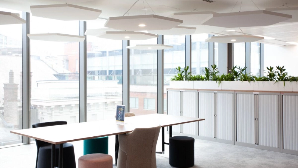 A Table with a few chairs around it next to a room divider of plants