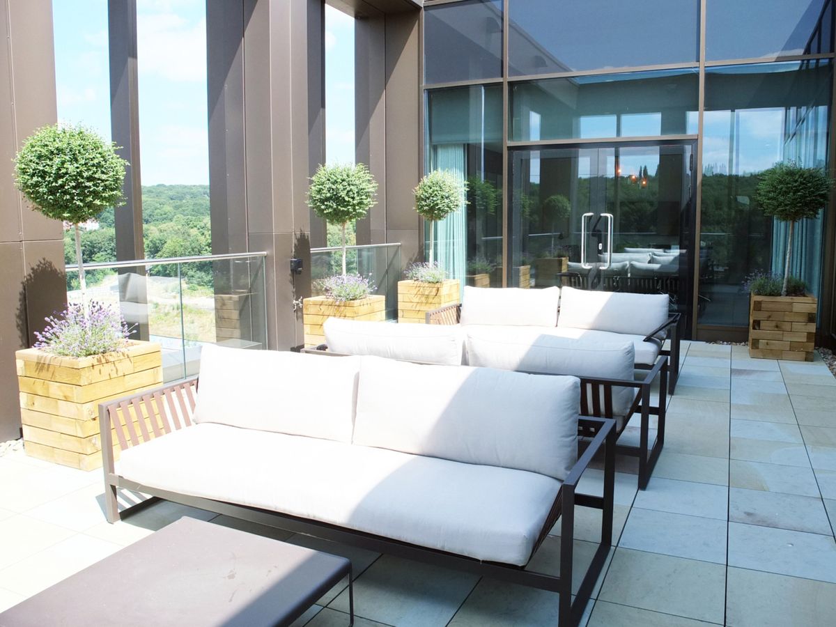 open area with plants, benches and white chairs