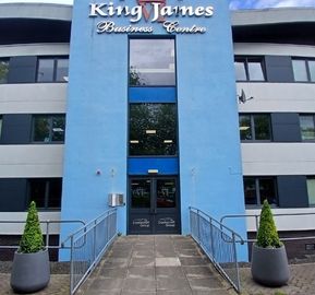 Exterior of King James Business Centre showing a blue entryway with a walkway bridge flanked by two potted topiary trees.