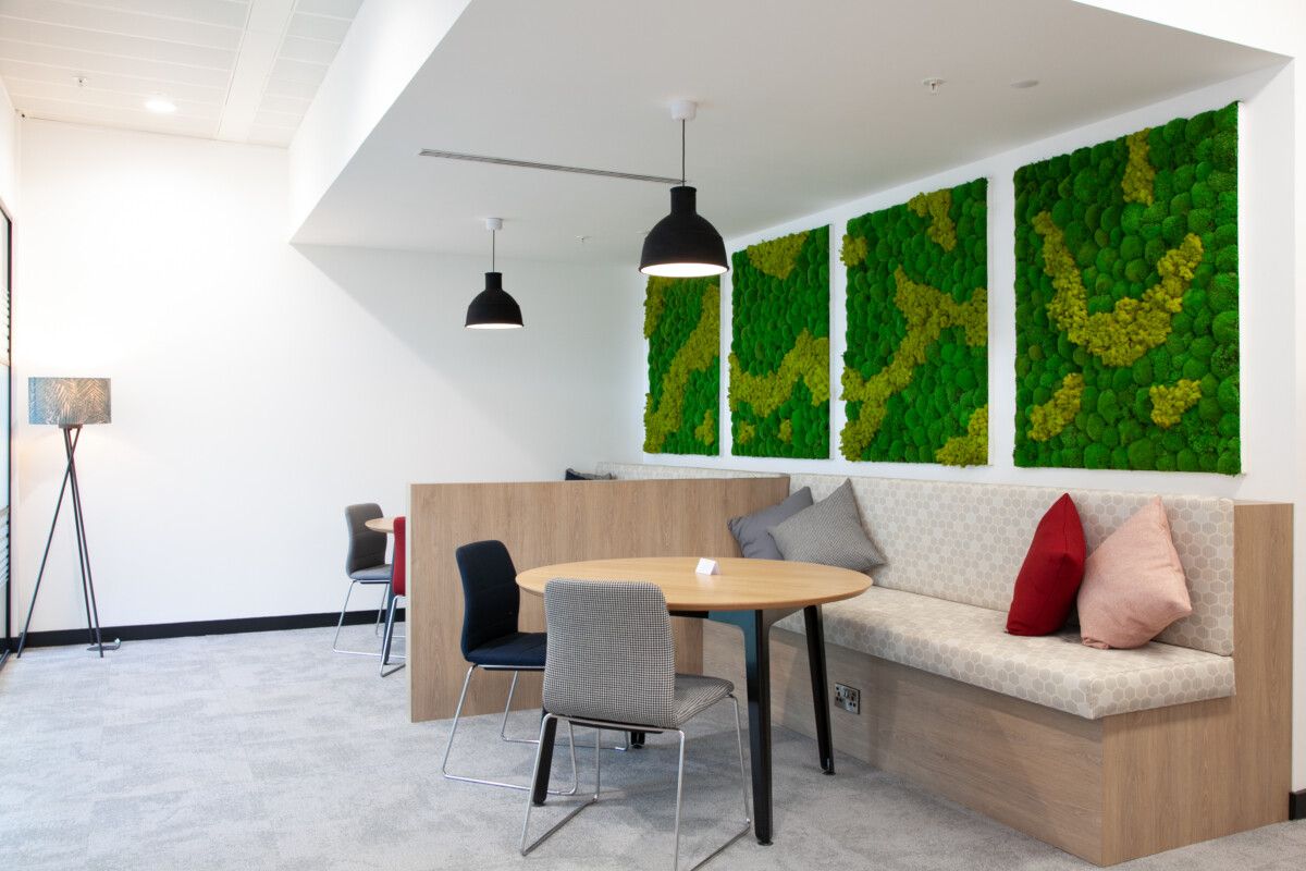 moss artwork on the wall behind tables and chairs