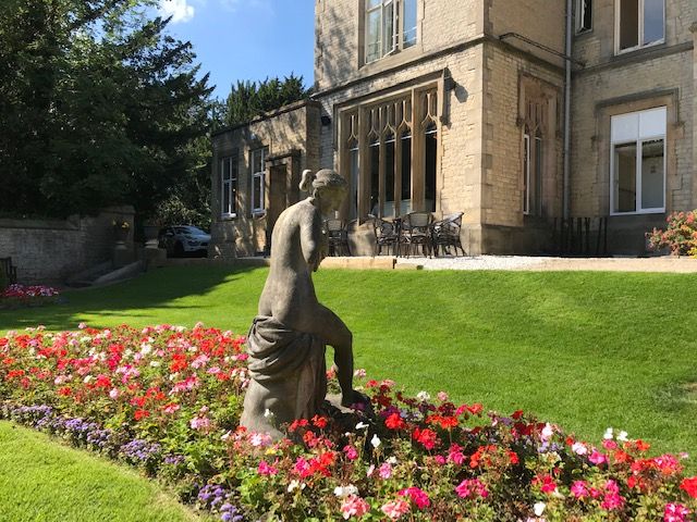 statue surrounded by beautiful flowers and greenery 