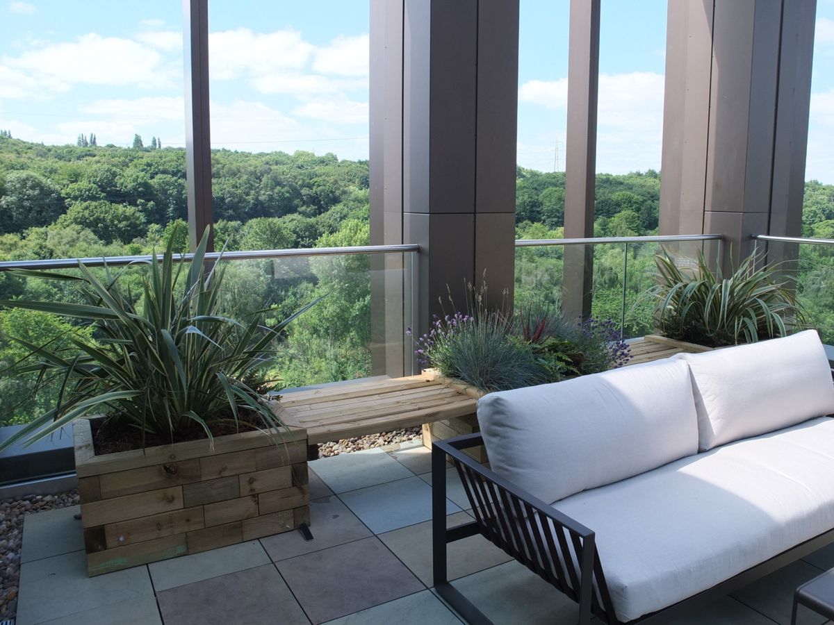 open area with plants, benches and white chairs