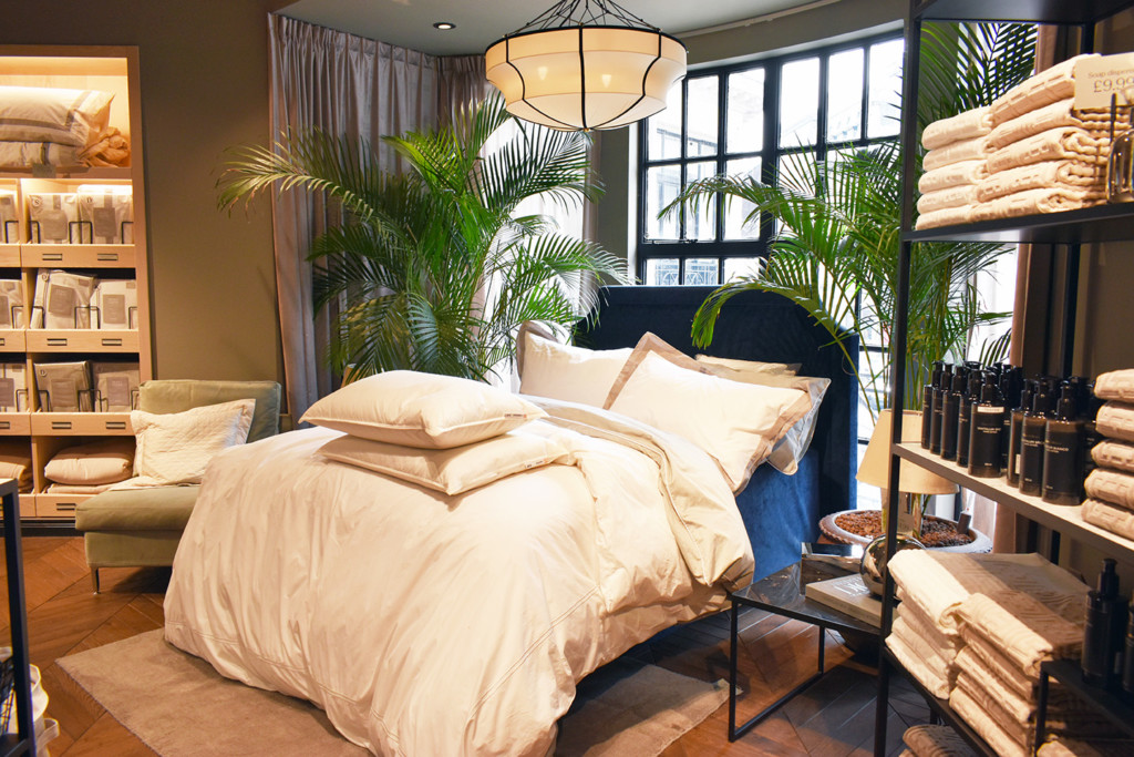 bed with large indoor plants beside it 