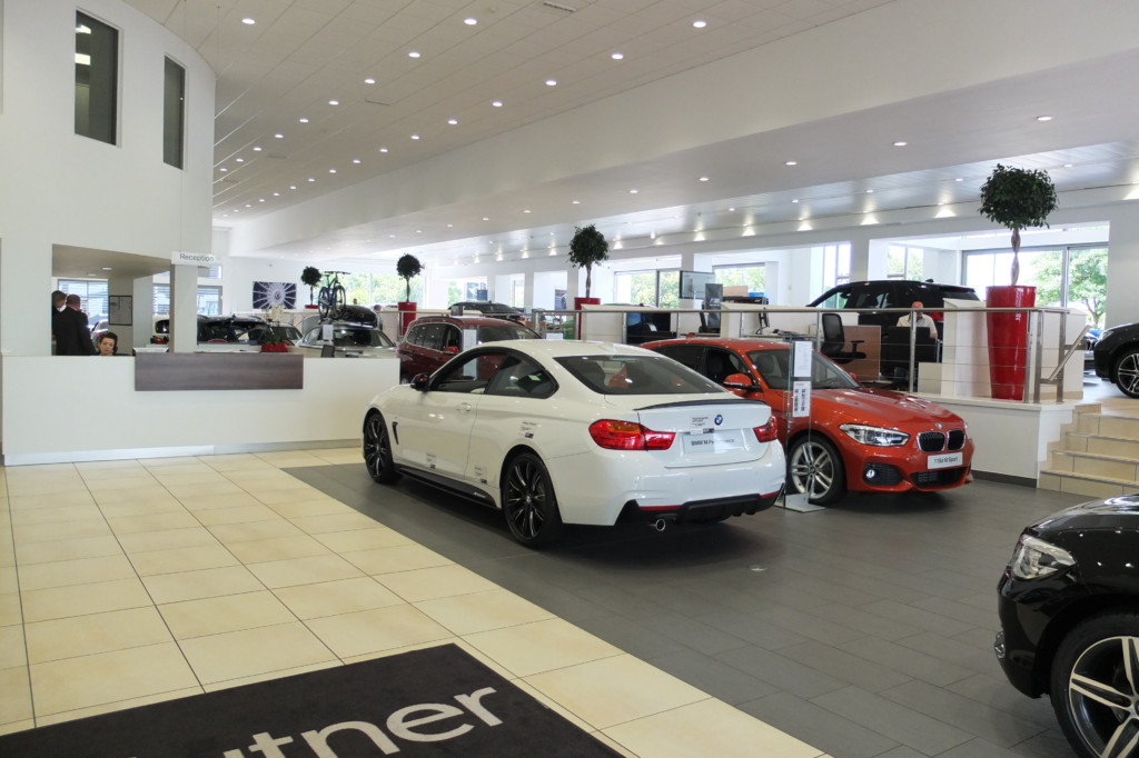 bmw cars on display in a building with plants