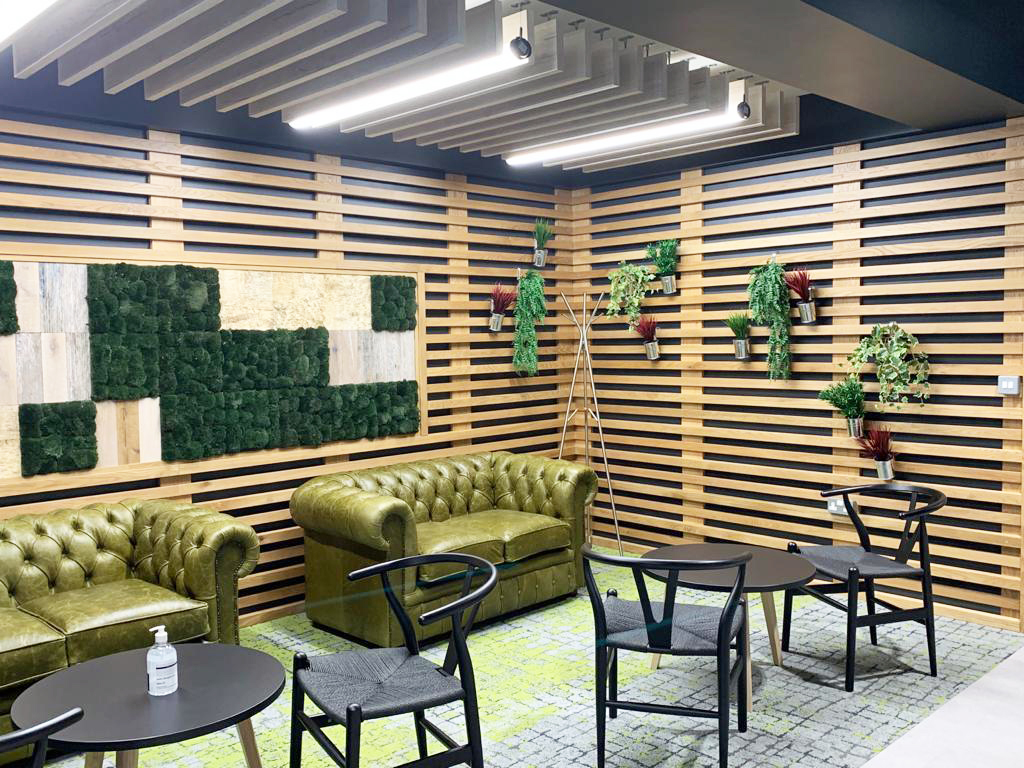 room with a green couch and plants on the wooden wall