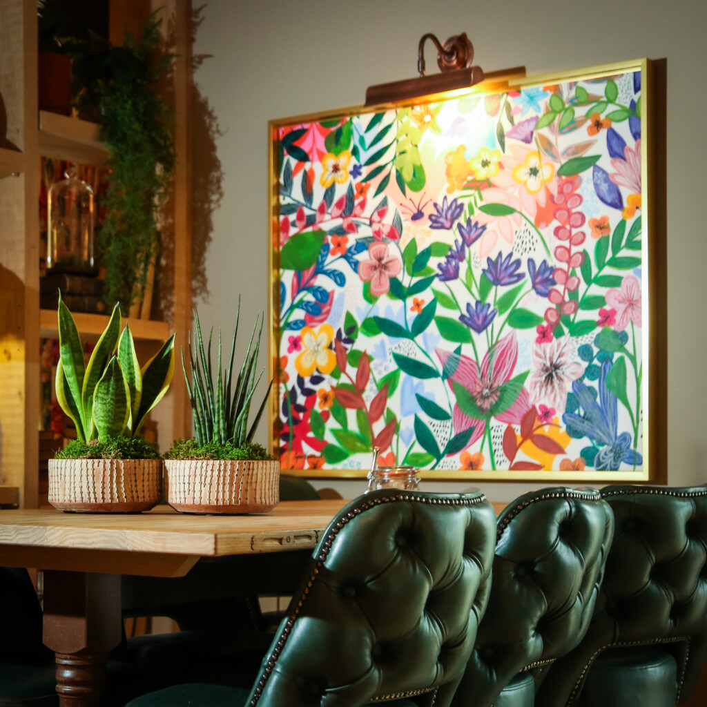 close up of indoor plants on table by artwork